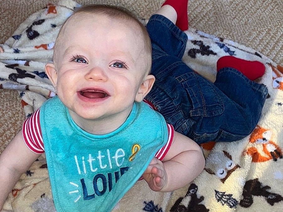 Ryder is registered to the contest to win money with this photo: baby, baby_toddler_clothing, cheek, child, eye, face, finger, happy, head, linens, mouth, nose, pattern, person, skin, sleeve, smile, t_shirt, textile, toddler