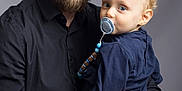 Aloïs a rejoint le concours — aidez-le/la à gagner de superbes lots ! adult, affection, baby, beard, blond_hair, blue_eyes, casual_clothing, child, closeup, family, gentle, holding, indoor, man, pacifier, parent, portrait, smile, studio, watch