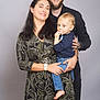 family, woman, man, child, toddler, smile, portrait, indoor, casual_clothing, holding, beard, bald, watch, toy, blue_jeans, long_hair, short_hair, standing, happy, studio