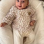 baby, infant, child, cushion, clothing, leopard_print, pants, soft_texture, indoors, cute, face, smile, eyes, skin, person, comfort, relaxing, furniture, cozy, expression