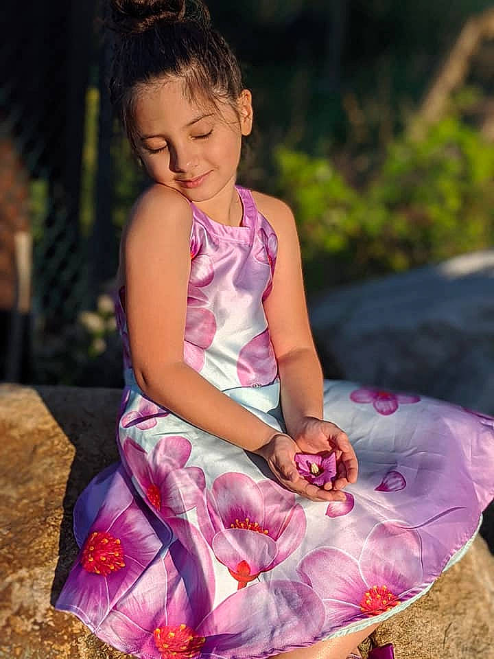 Lily is registered to the contest to win money with this photo: child_model, day_dress, dress, embellishment, happy, joy, laugh, lavender, magenta, people_in_nature, person, photo_shoot, pink, purple, sitting