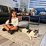 Pickles is registered to the contest to win money with this photo: boots, carpet, casual_clothing, cat, child, coffee_table, decor, flower_arrangement, girl, home, indoor, living_room, long_hair, pet, relaxed, sitting, smile, sofa, window_blinds, wood_floor