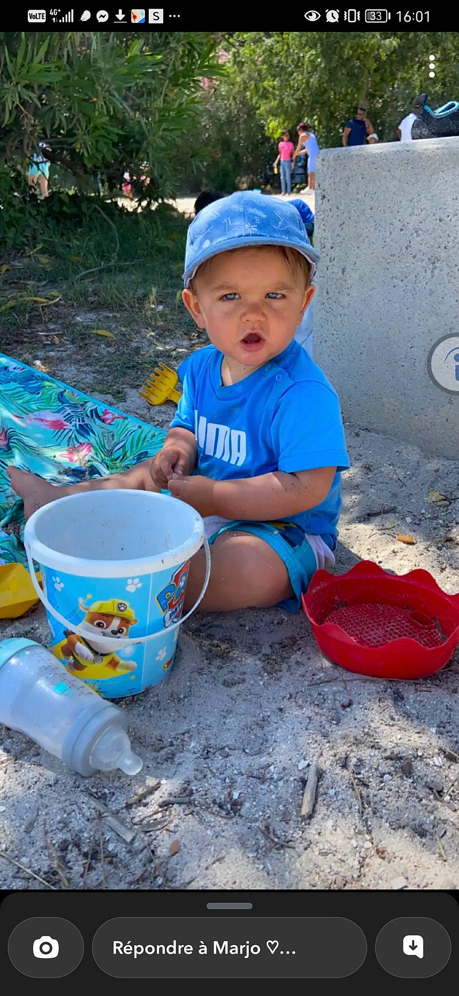 Lohan participe au concours pour gagner de l'argent avec cette photo : baby_toddler_clothing, baseball_cap, blue, bucket, cap, child, electric_blue, fun, hat, headwear, leisure, person, personal_protective_equipment, plant, plastic, play, recreation, shorts, sitting, soil
