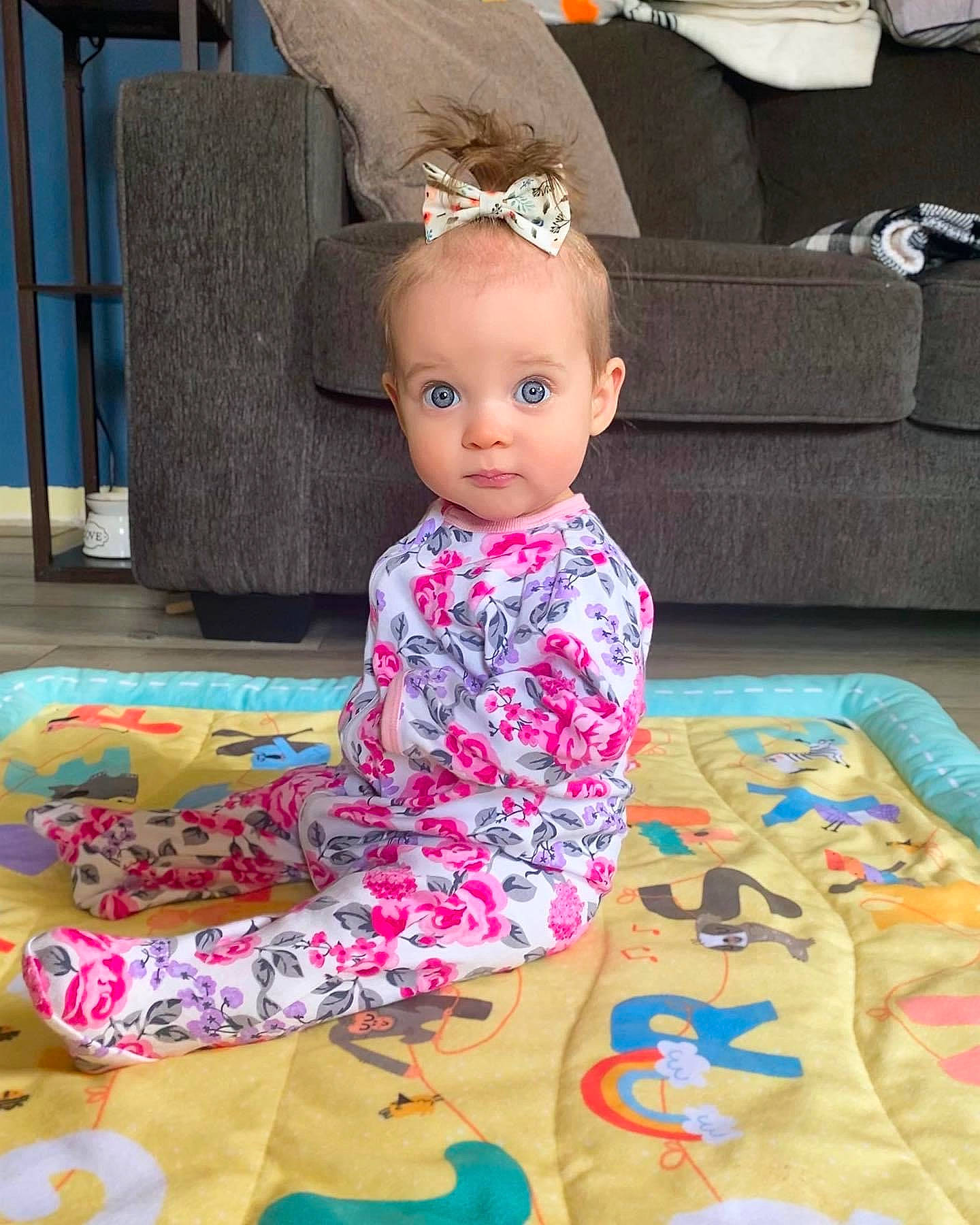 June is registered to the contest to win money with this photo: baby, baby_toddler_clothing, child, fashion_accessory, fashion_design, floor, flooring, fun, head, jewellery, linens, magenta, pattern, person, pink, playmat, room, sitting, sleeve, textile