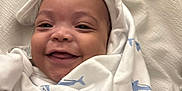 Aspen And Denver is registered to the contest to win money with this photo: baby, smiling, blanket, white, blue, shark_pattern, hood, cute, infant, face, portrait, happy, cozy, soft, child, wrapped, lying_down, fabric, texture, closeup