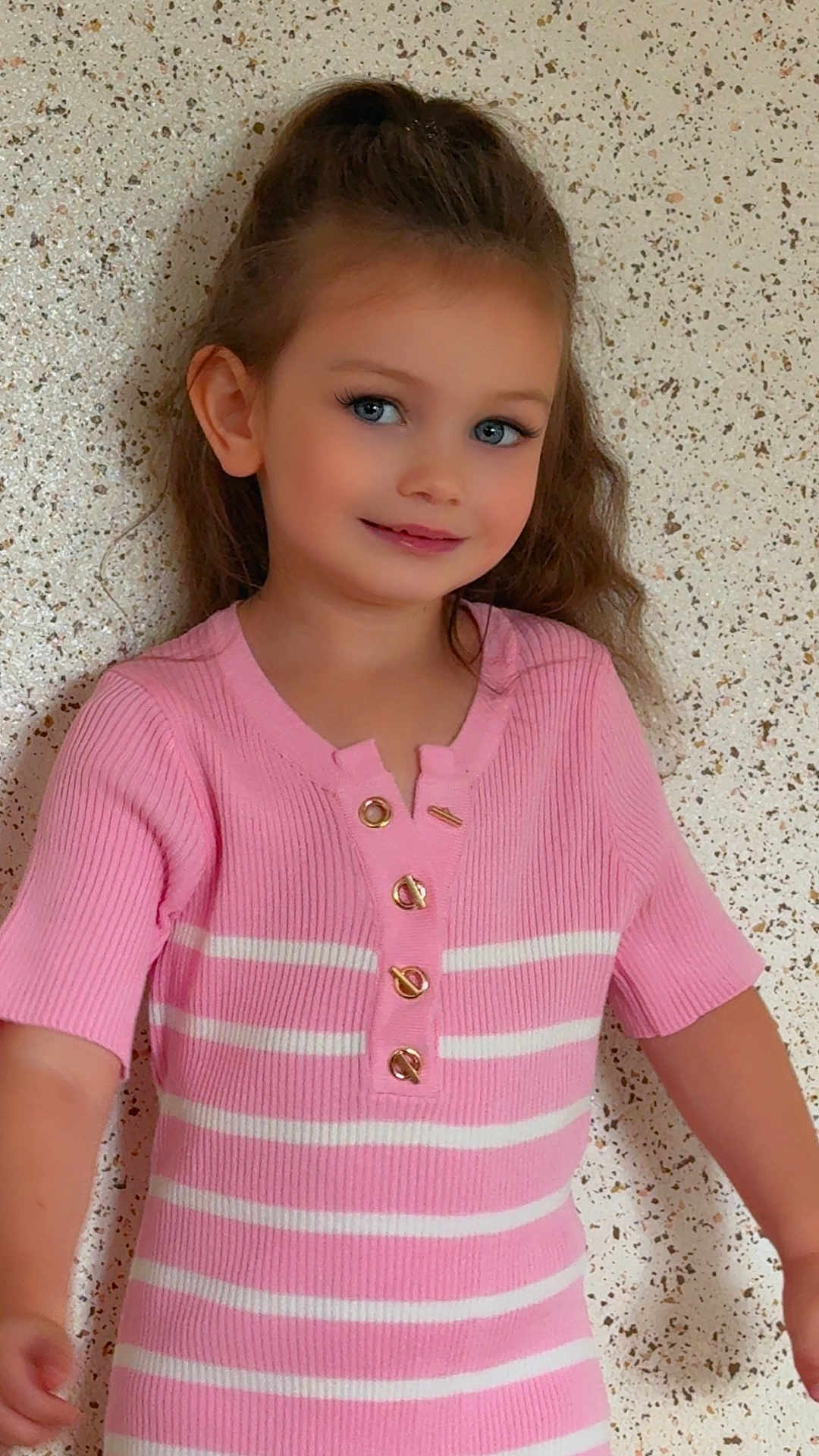 Liya participe au concours pour gagner de l'argent avec cette photo : child, girl, smile, portrait, blue_eyes, pink_dress, striped_clothing, long_hair, buttoned_top, indoor, wall_background, happy, cute, fashion, person, young_child, casual, standing, closeup, human