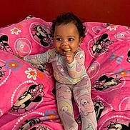 Naeliya joined the competition — help win amazing prizes! baby, child, comfort, curly_hair, cute, happy, indoors, infant, minnie_mouse, pajamas, person, pink_blanket, playful, portrait, red_wall, sitting, smile, soft_blanket, teething_toy, toy