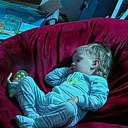 Logan joined the competition — help win amazing prizes! child, toddler, sleeping, baby, pajamas, couch, indoor, portrait, face, blond_hair, closed_eyes, relaxed, lounge, home, furniture, red_couch, blue_lighting, baby_supplies, star_decoration, nap