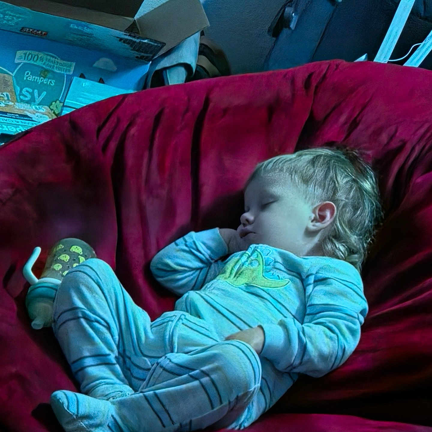 Logan joined the competition — help win amazing prizes! child, toddler, sleeping, baby, pajamas, couch, indoor, portrait, face, blond_hair, closed_eyes, relaxed, lounge, home, furniture, red_couch, blue_lighting, baby_supplies, star_decoration, nap