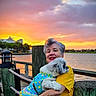 Channel Rios joined the competition — help win amazing prizes! clothing, clouds, colorful, dock, dog, evening, fence, fur, happy, holding, leash, nature, outdoor, pet, portrait, sky, smile, sunset, water, woman