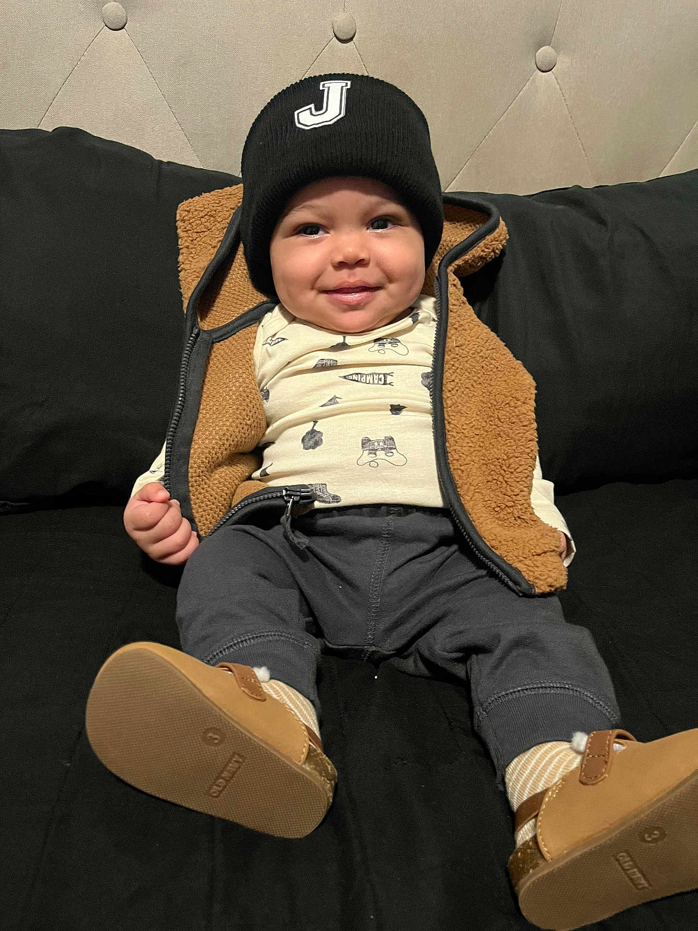Jasonny joined the competition — help win amazing prizes! baby, child, smiling, beanie, vest, brown, black_couch, shoes, socks, pants, shirt, indoor, seated, cute, infant, portrait, cozy, happy, clothing, face