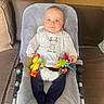 baby, baby_rocker, child, clothing, colorful_toy, couch, cute, face, furniture, happy, home, indoor, infant, person, plush, remote_control, seat, sitting, smile, toy