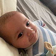 Lyam a rejoint le concours — aidez-le/la à gagner de superbes lots ! baby, infant, smile, striped_clothes, pacifier, bed, pillow, blanket, portrait, cute, face, cheek, eyes, lying_down, soft_light, indoors, young_child, nursery, stuffed_toy, closeup