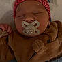 baby, newborn, infant, pacifier, sleeping, hat, pink_hat, blanket, blue_blanket, onesie, brown_clothing, face, cheeks, closed_eyes, hand, cozy, portrait, crib, soft_texture, cute