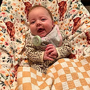 Jolee joined the competition — help win amazing prizes! baby, child, smile, blanket, pacifier, cozy, pattern, animal_print, cheerful, cute, infant, clothing, indoor, face, portrait, comfort, happy, sitting, plaid, fabric