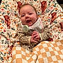 baby, child, smile, blanket, pacifier, cozy, pattern, animal_print, cheerful, cute, infant, clothing, indoor, face, portrait, comfort, happy, sitting, plaid, fabric