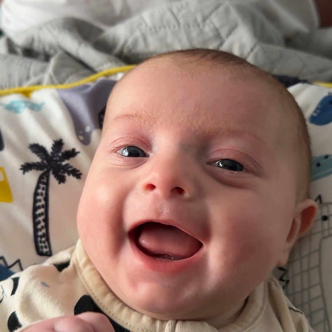 Arthur-James is registered to the contest to win money with this photo: baby, babylaughing, bed, bodypart, clothing, coat, cushion, face, furniture, happy, head, homedecor, jacket, laughing, newborn, person, photography, portrait, quilt, smile