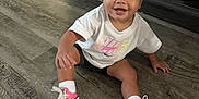 Maeve joined the competition — help win amazing prizes! toddler, child, sitting, floor, wooden_floor, sneakers, pink_shoes, white_tshirt, nike_logo, happy, smiling, indoors, playroom, toys, storage_bin, shorts, baby, cute, person, casual_clothing