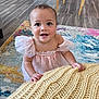 Maeve joined the competition — help win amazing prizes! toddler, child, smiling, pink_dress, knit_blanket, indoor, carpet, wood_floor, furniture, curly_hair, face, eyes, hands, cute, baby, home, colorful, patterned_rug, happy, portrait