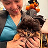 Lincoln is registered to the contest to win money with this photo: person, dog, puppy, smile, indoor, holding, cute, fluffy, toy, stuffed_animal, face, hands, happy, black, brown, furniture, chair, wood_floor, casual_clothing, background