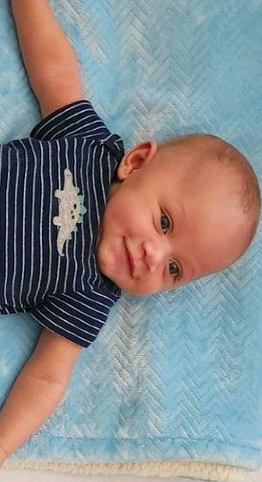 Elijah is registered to the contest to win money with this photo: arm, baby, baby_toddler_clothing, cheek, child, elbow, eye, finger, gesture, happy, human_body, linens, nose, pattern, person, skin, sleeve, smile, textile, toddler