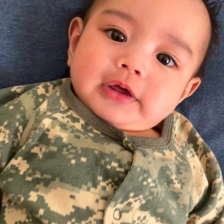 Aedan joined the competition — help win amazing prizes! baby, blue_background, camouflage, child, clothing, cute, expression, eyes, face, hair, head, indoors, infant, lying_down, onesie, person, portrait, skin, soft_texture, young