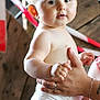 baby, child, diaper, skin, face, hand, adult_hand, holding, standing, indoor, person, cute, plump, expression, looking, background, wood, tape, arm, portrait