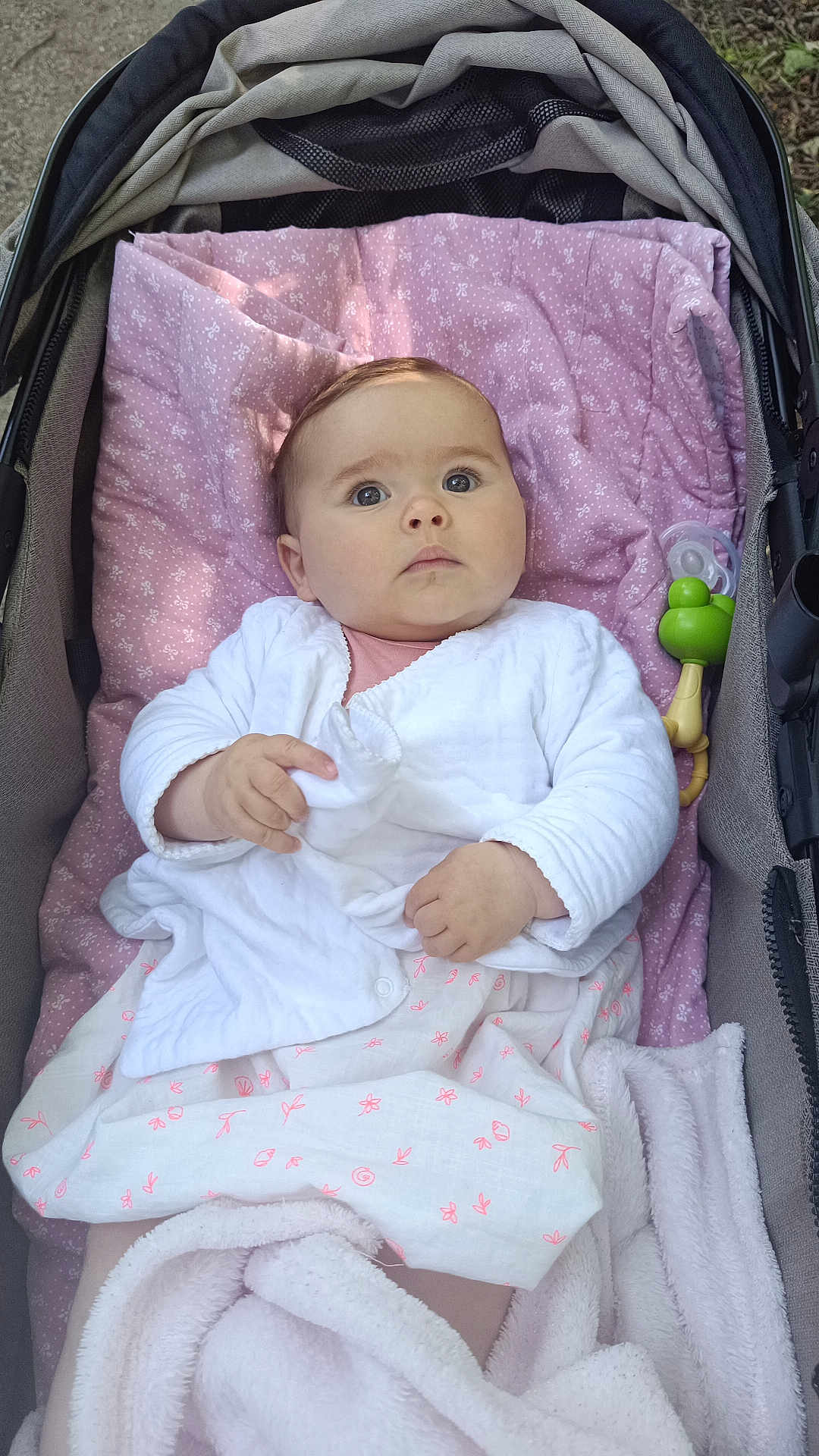 Gaby participe au concours pour gagner de l'argent avec cette photo : baby, infant, stroller, blanket, pacifier, baby_clothing, pink, white, outdoor, child, cute, portrait, person, fabric, toy, relaxing, soft_texture, young_child, comfort, baby_accessory