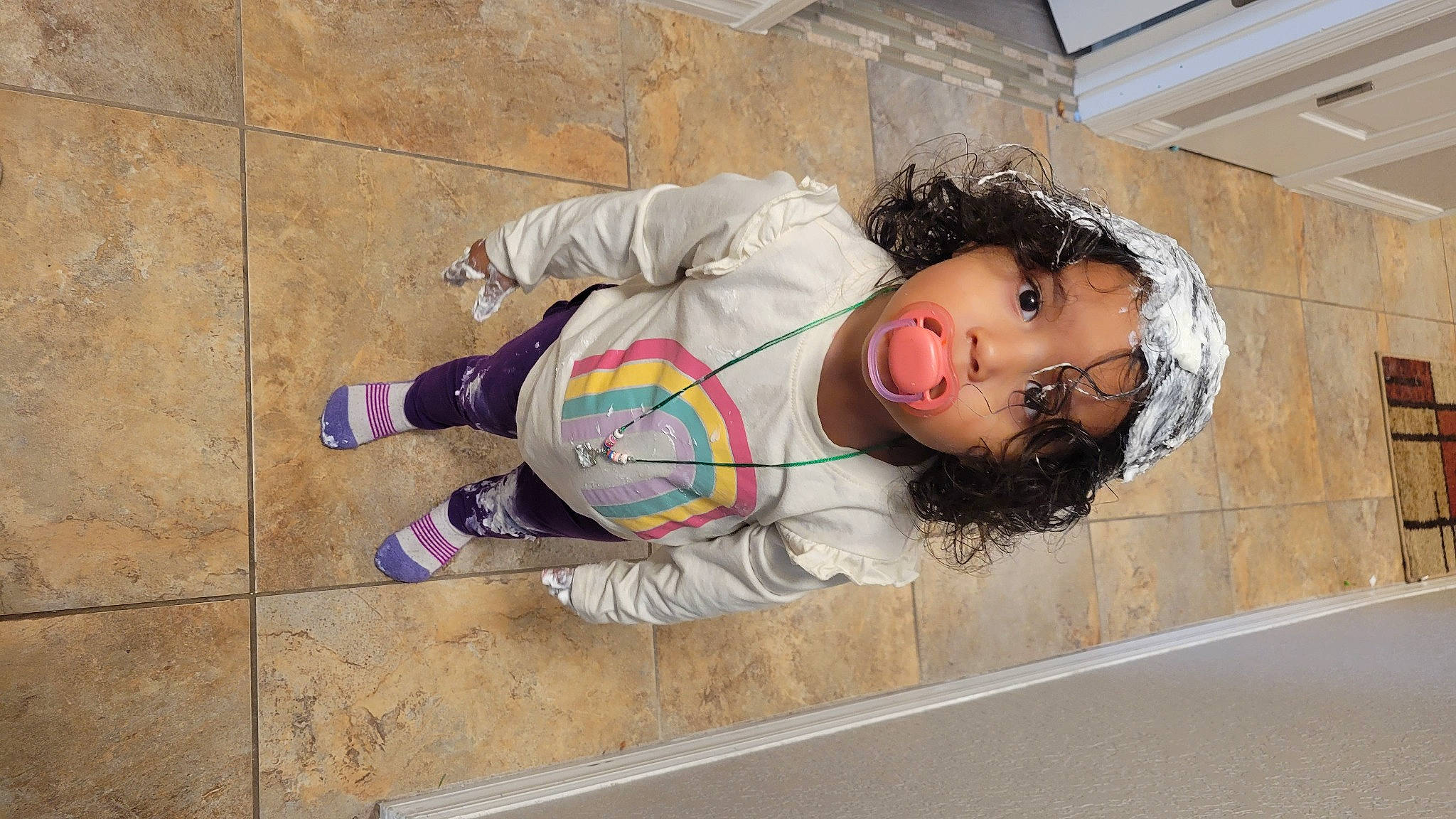 Eniyah is registered to the contest to win money with this photo: child, comfort, concrete, eyewear, floor, flooring, fun, human_leg, leisure, pattern, person, personal_protective_equipment, sidewalk, sitting, thigh, toddler, wood