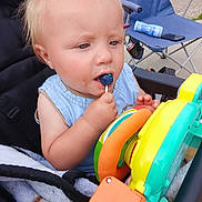 Bryson is registered to the contest to win money with this photo: baby, blanket, blue, chair, child, clothing, curious, expression, face, hand, lollipop, outdoor, person, plastic, play, seat, stroller, summer, toddler, toy