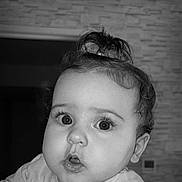 Tyana participe au concours pour gagner de l'argent avec cette photo : baby, black_and_white, child, close_up, clothing, cozy, curiosity, curly_hair, cute, expression, face, indoor, infant, person, ponytail, portrait, skin, soft_lighting, wide_eyes, young
