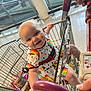 Piper joined the competition — help win amazing prizes! adult_hand, baby, blue_eyes, child, colorful_dress, curious, floor, food_items, grocery, indoor, joyful, metal_bars, person, rainbow_pattern, seatbelt, shopping, shopping_cart, smiling, store, toddler