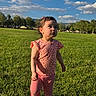 Athena joined the competition — help win amazing prizes! child, toddler, grass, park, outdoor, sky, clouds, tree, greenery, sunlight, casual_clothing, pink_clothing, curious_expression, standing, nature, daytime, playing, young_child, scenic, leisure