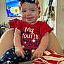 american_flag_pattern, baby, blue_clothing, child, cute, fourth_of_july, furniture, happy, headband, home, indoors, infant, patriotic, person, red_clothing, sitting, smiling, stars, stripes, television