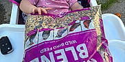 Myla is registered to the contest to win money with this photo: baby, bag, bird_images, bird_seed, car_key, child, closeup, curious, daylight, feeding_time, high_chair, outdoor, patterned_fabric, pavement, person, pink_clothing, plastic_tray, seat, snack, young_child
