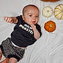 baby, black_clothing, blanket, checkered_shorts, child, curious_expression, cute, decor, face, fall_theme, hand, indoor, infant, lying_down, orange, portrait, pumpkin, small_pumpkins, striped_socks, white