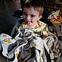 toddler, child, laundry_basket, clothing, indoor, playful, tongue_out, happy, face, person, fabric, textile, household, floor, brick_wall, casual, cute, smiling, baby, soft_light