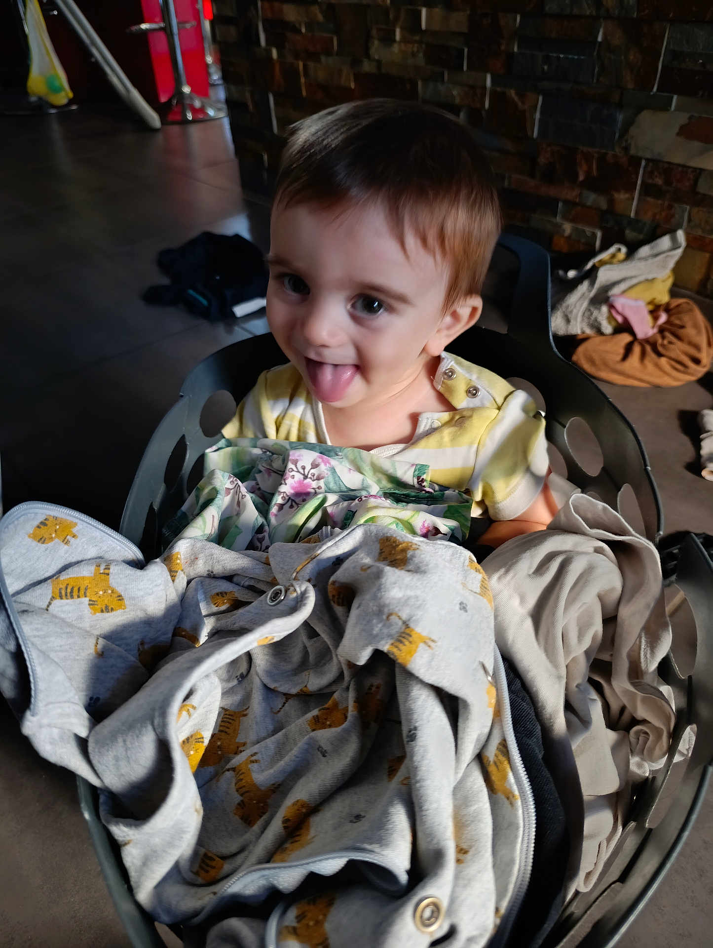 Eden a rejoint le concours — aidez-le/la à gagner de superbes lots ! toddler, child, laundry_basket, clothing, indoor, playful, tongue_out, happy, face, person, fabric, textile, household, floor, brick_wall, casual, cute, smiling, baby, soft_light