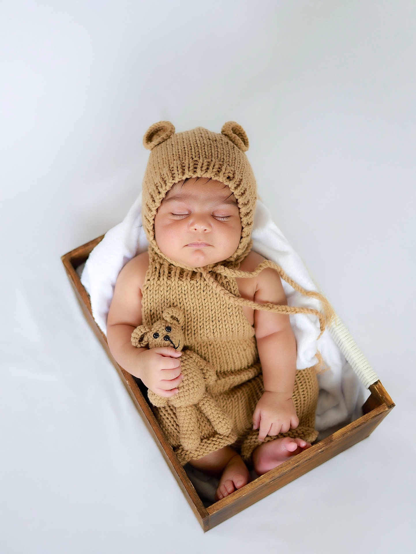 Divansh Prasad is registered to the contest to win money with this photo: baby, sleeping, knitted_clothing, bear_hat, wooden_box, blanket, soft_toy, teddy_bear, infant, cute, peaceful, portrait, newborn, hand, foot, indoors, cozy, child, hat, knitwear