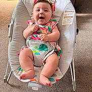 Elaina joined the competition — help win amazing prizes! baby, smiling, baby_rocker, floral_dress, carpet, furniture, indoor, child, happy, seatbelt, turtle_design, person, infant, cute, home, legs, hands, face, sitting, colorful