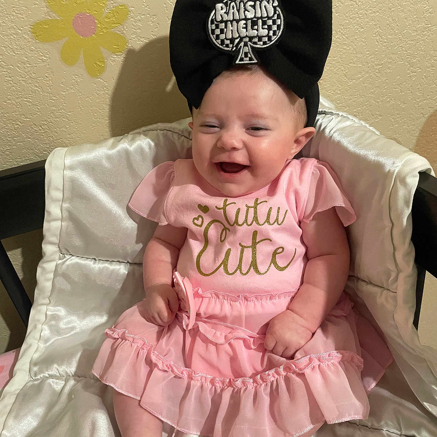 Khloe-Jo joined the competition — help win amazing prizes! baby, black_bow, child, clothing, cushion, cute, flower_decals, happy, headband, headwear, indoors, infant, joyful, person, pink_dress, portrait, satin, sitting, smile, wall