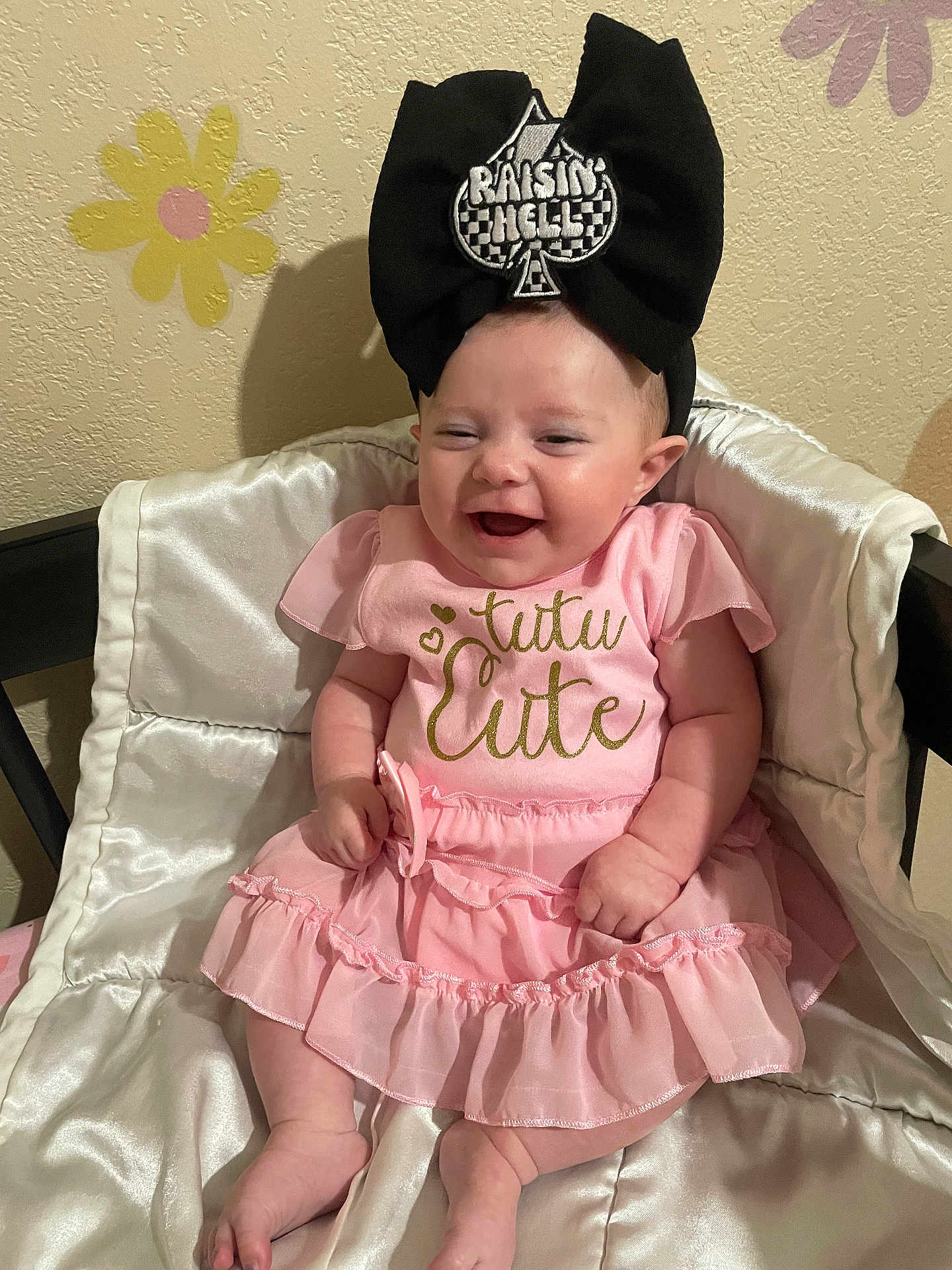 Khloe-Jo joined the competition — help win amazing prizes! baby, infant, pink_dress, headband, black_bow, smile, sitting, cushion, satin, wall, flower_decals, cute, happy, indoors, child, clothing, person, headwear, joyful, portrait