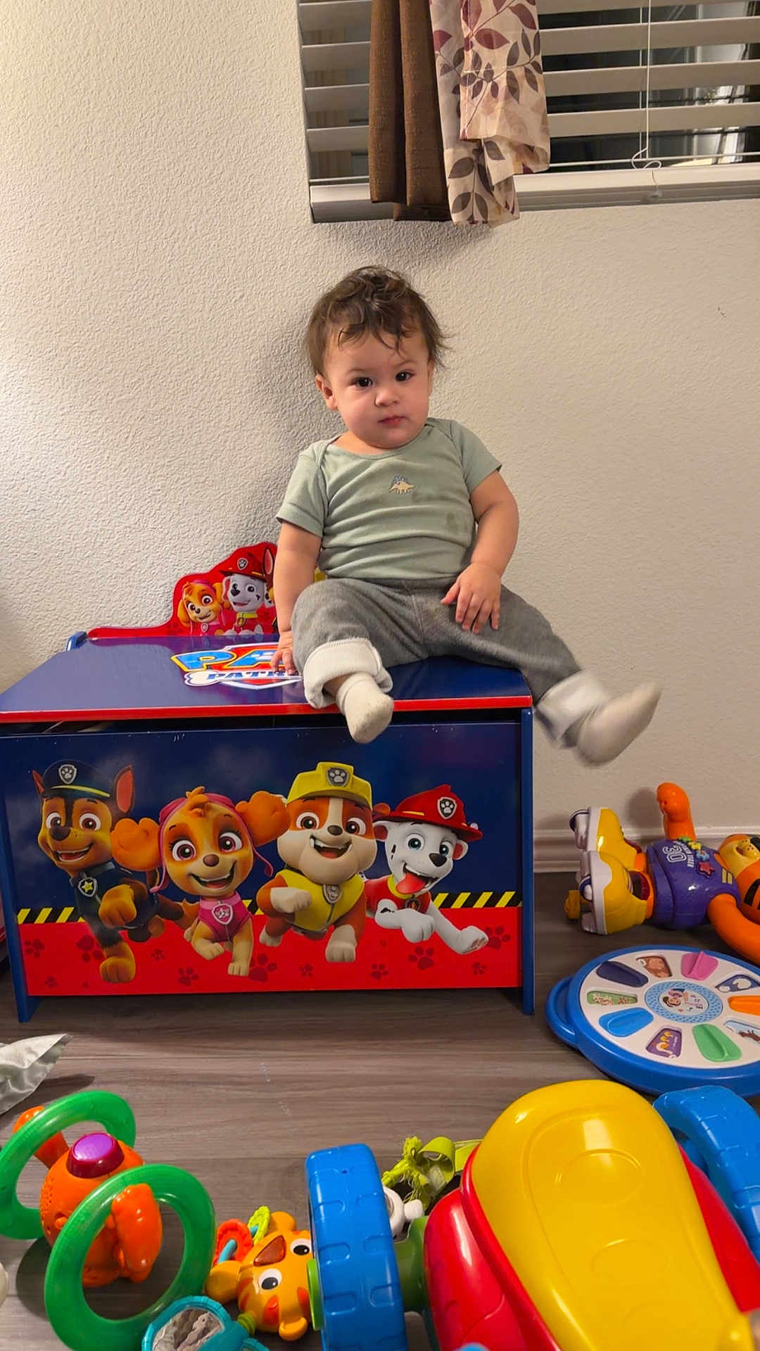 Noah joined the competition — help win amazing prizes! toddler, child, toy_chest, paw_patrol, indoor, curtains, window, floor, toys, plastic_toys, colorful, clothing, sitting, face, person, pants, sock, hair, wall, room