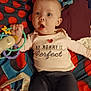 Hope is registered to the contest to win money with this photo: baby, infant, child, toy, blanket, clothing, face, expression, lying_down, pacifier, colorful, playful, cute, hand, earrings, fabric, comfort, surprised, person, indoor