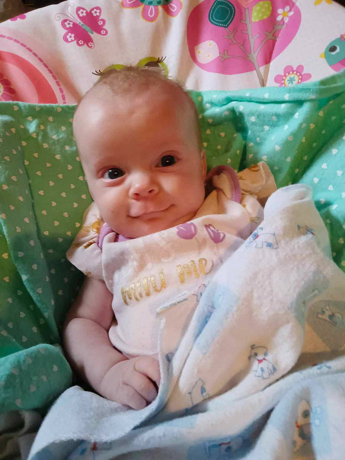 Ellianna is registered to the contest to win money with this photo: baby, baby_products, baby_toddler_clothing, bedding, cheek, child, comfort, eye, face, happy, head, linens, pattern, person, pink, room, sitting, skin, smile, textile