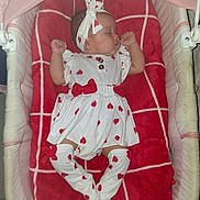 Jazlyn is registered to the contest to win money with this photo: baby, sleeping, infant, bassinet, blanket, red, white, heart_pattern, headband, socks, cute, cozy, child, clothing, resting, indoor, soft, comfort, adorable, peaceful