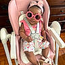 baby, child, high_chair, sunglasses, bow, pink, floral_dress, sandals, seated, portrait, indoor, dresser, wooden_floor, home, fashion, cute, infant, harness, smiling, accessories