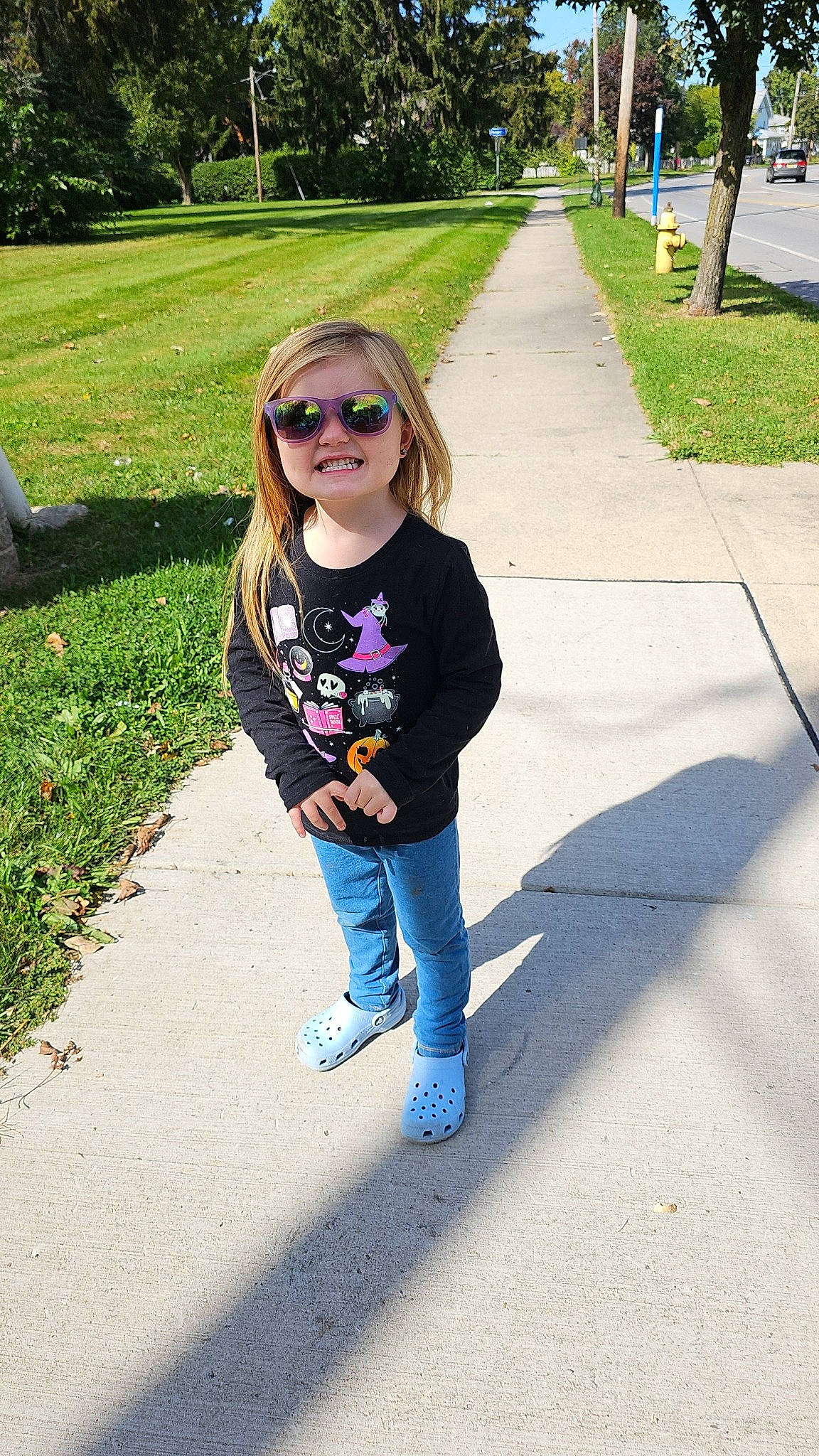 Ryleigh is registered to the contest to win money with this photo: asphalt, denim, electric_blue, eyewear, fun, glasses, grass, happy, joy, leisure, long_hair, person, plant, recreation, sleeve, smile, sunglasses, t_shirt, toddler, tree