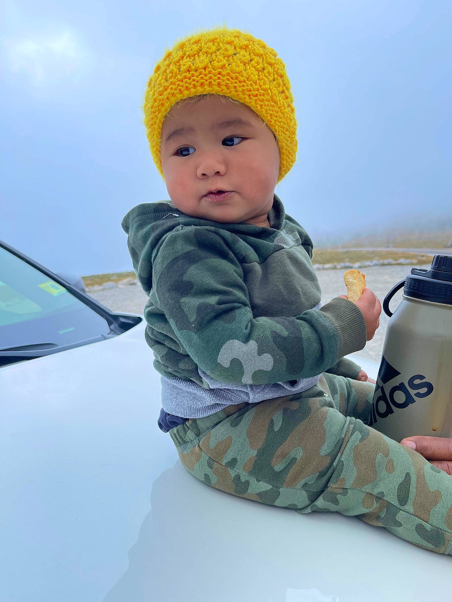 Melvin is registered to the contest to win money with this photo: automotive_exterior, automotive_lighting, automotive_window_part, baby, baby_toddler_clothing, beanie, camouflage, cap, car, child, fun, headwear, hood, knit_cap, military_camouflage, person, personal_luxury_car, sky, sleeve, toddler
