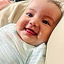 baby, infant, smile, tongue, close_up, face, eyes, lying_down, onesie, striped_clothing, cute, happy, soft_surface, indoors, child, skin, cheeks, head, expression, person